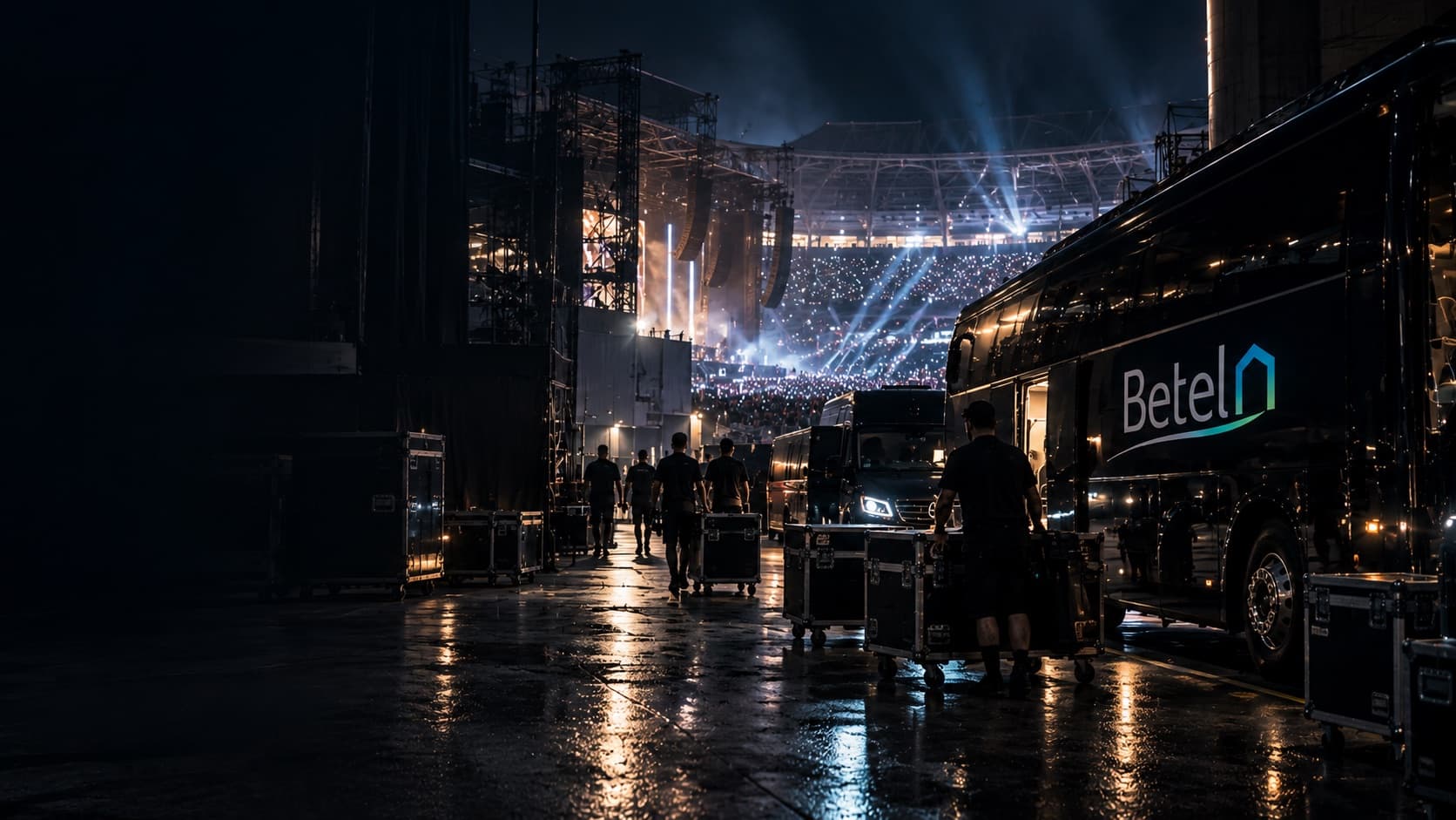 Tecnici spostano i flight case nel backstage di un concerto in stadio, accanto al bus Betel